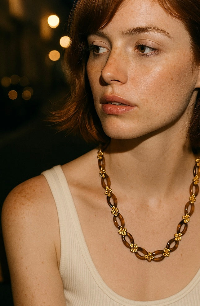 Woman wearing a long brown necklace against a neutral background