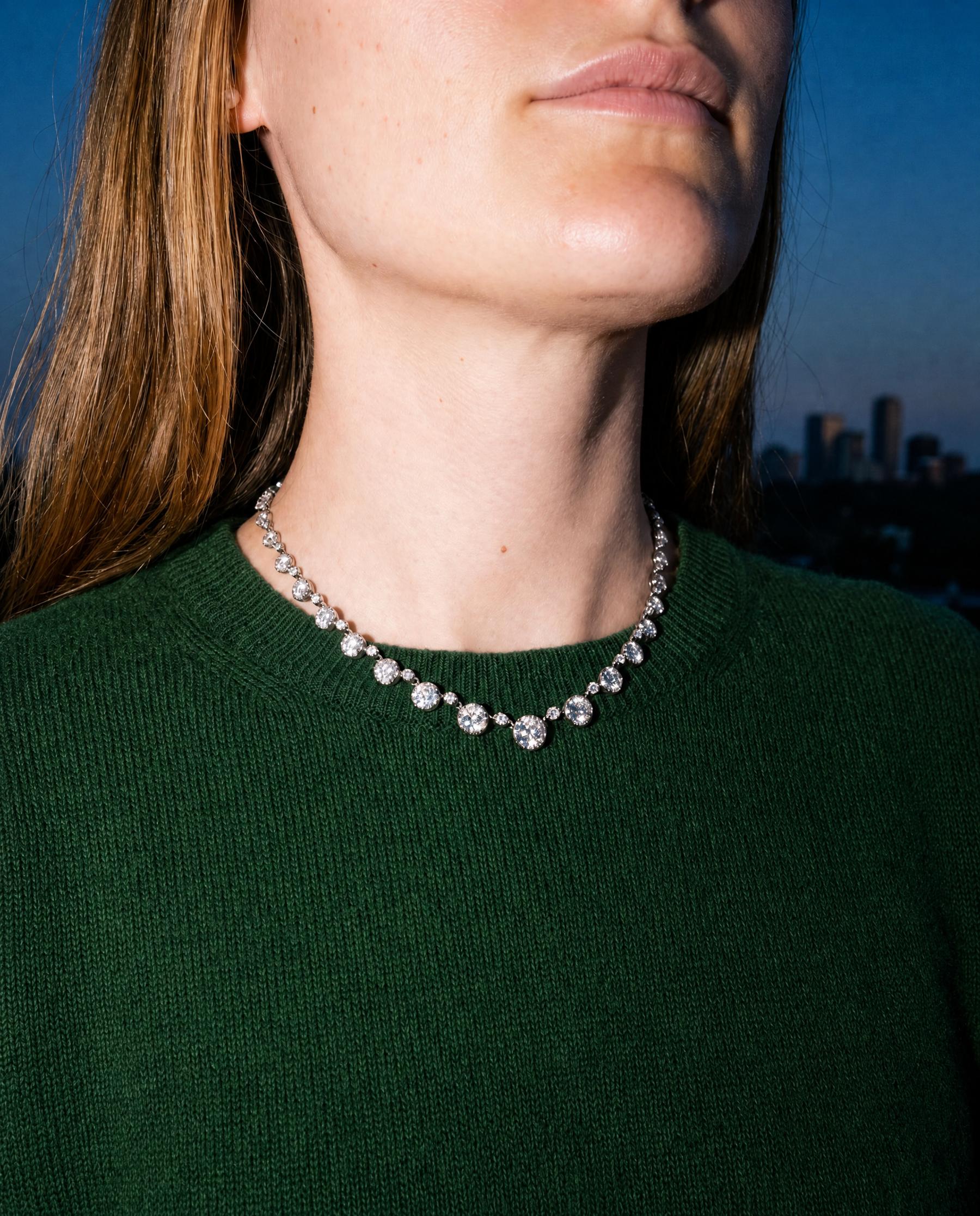 A diamond rivière necklace worn with a green sweater